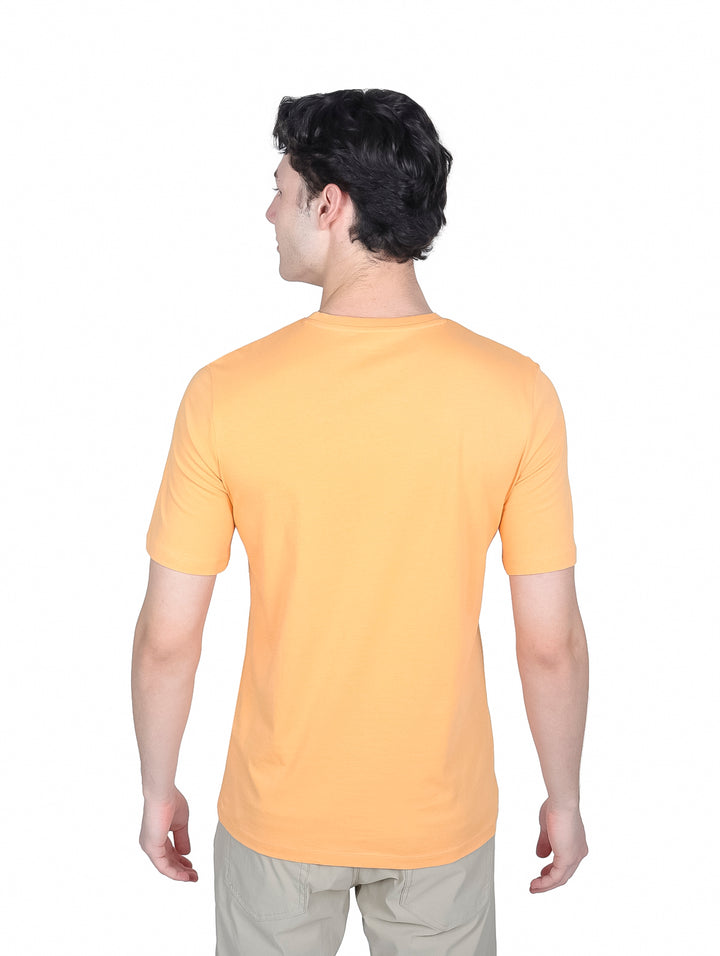 Hombre vistiendo playera naranja de manga corta con logo Jack &amp; Jones y pantalones beige.