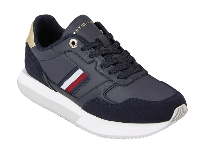 Tenis Tommy Hilfiger azul marino con suela blanca, detalles dorados en el talón y rayas laterales.