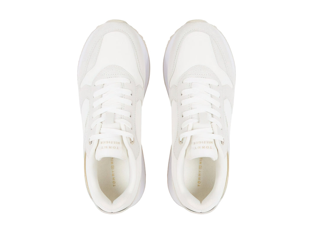 Tenis blancos Tommy Hilfiger Elevated Feminine Runner con detalles dorados y suela blanca.