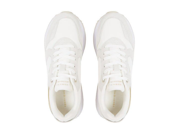 Tenis blancos Tommy Hilfiger Elevated Feminine Runner con detalles dorados y suela blanca.