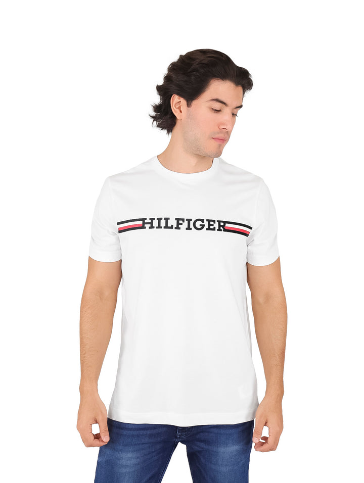 Hombre vistiendo camiseta blanca de manga corta Tommy Hilfiger con logotipo gráfico en el pecho.
