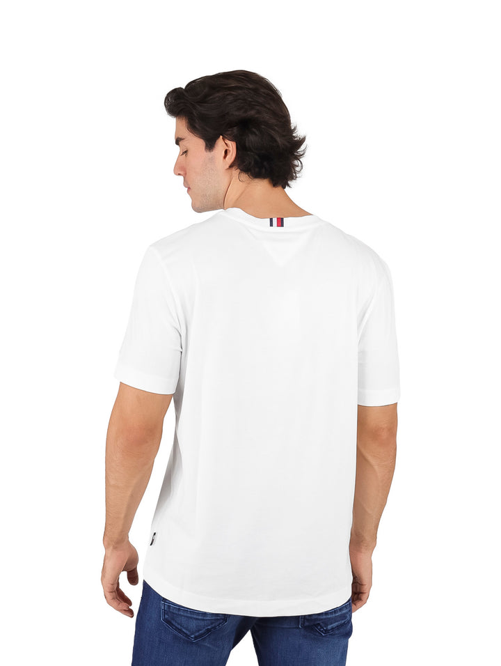 Hombre vistiendo camiseta blanca de manga corta Tommy Hilfiger con logotipo gráfico en el pecho.