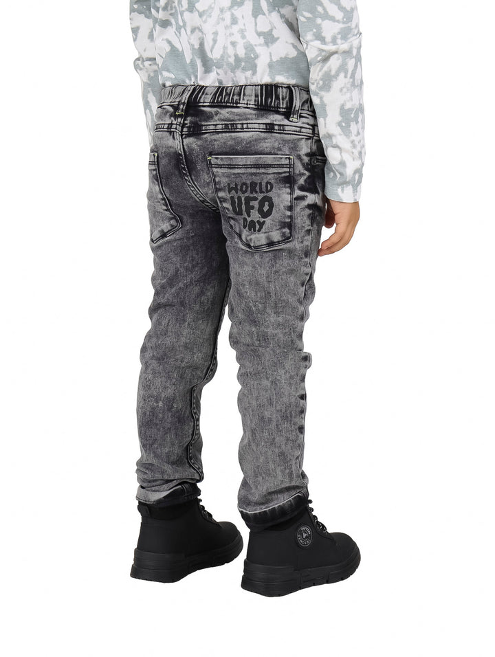 Pantalón de mezclilla gris para niño con estampado de alienígena y accesorio colgante.