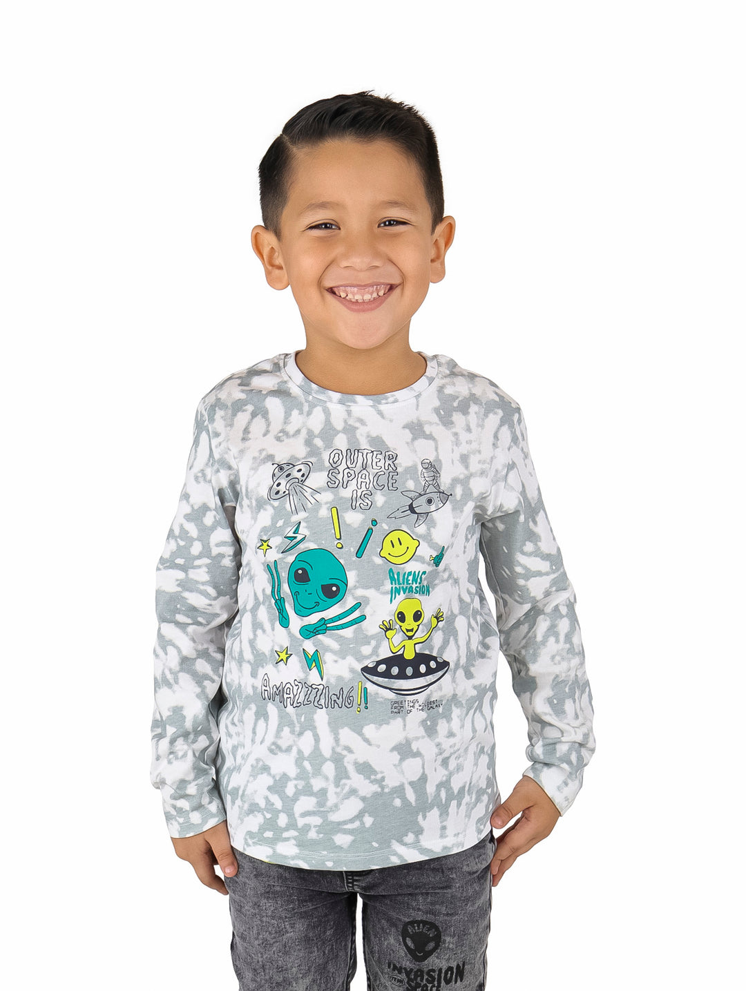 Niño vistiendo camiseta manga larga blanca y gris con efecto tie-dye y estampado de alienígenas y ovnis.