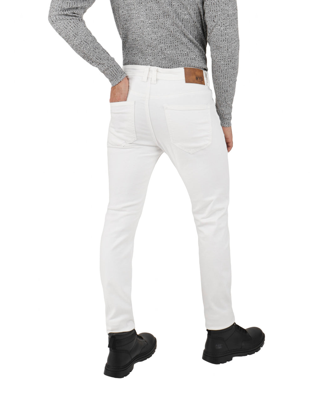 Hombre vistiendo pantalones jeans blancos de corte ajustado y botas negras.