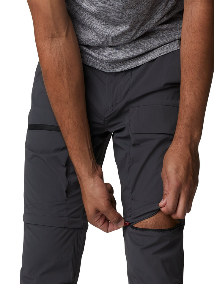 Hombre vistiendo pantalones Columbia color gris oscuro con función convertible mediante cremallera en la rodilla.