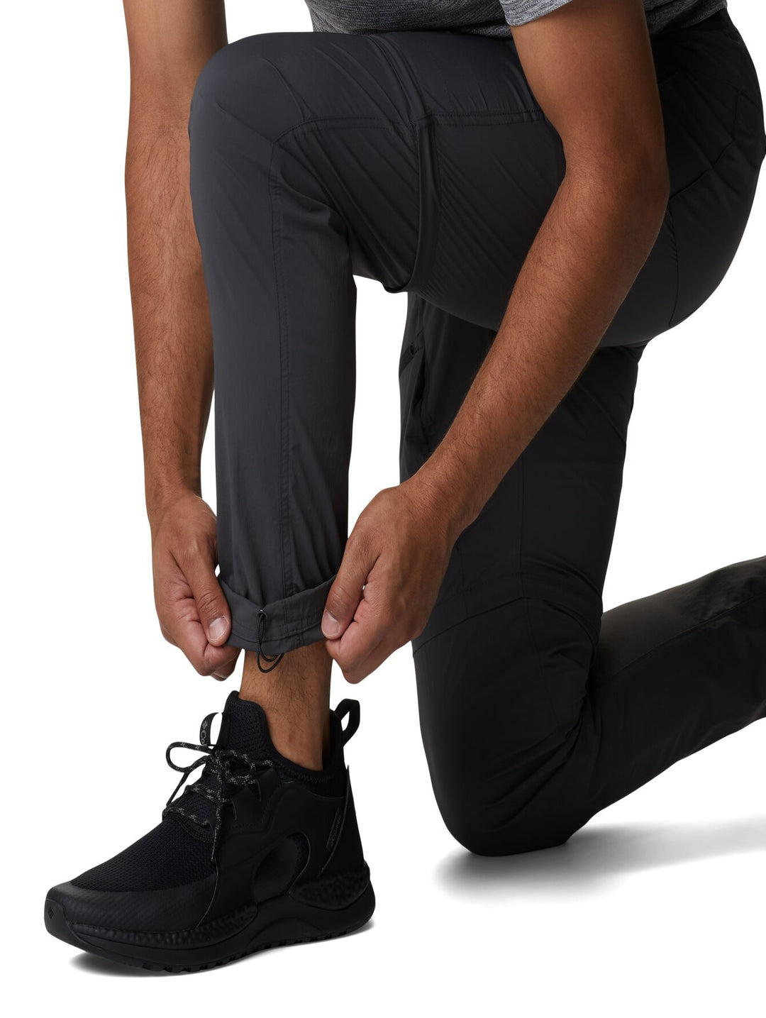 Hombre vistiendo pantalones Columbia color gris oscuro con función convertible mediante cremallera en la rodilla.