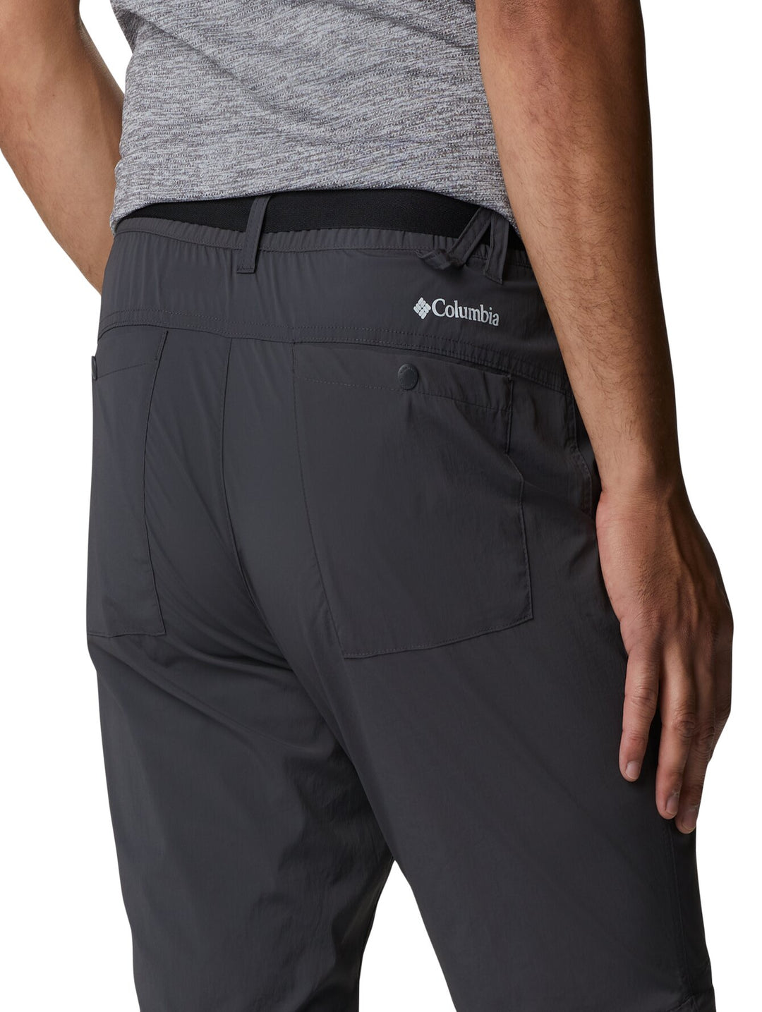 Hombre vistiendo pantalones Columbia color gris oscuro con función convertible mediante cremallera en la rodilla.