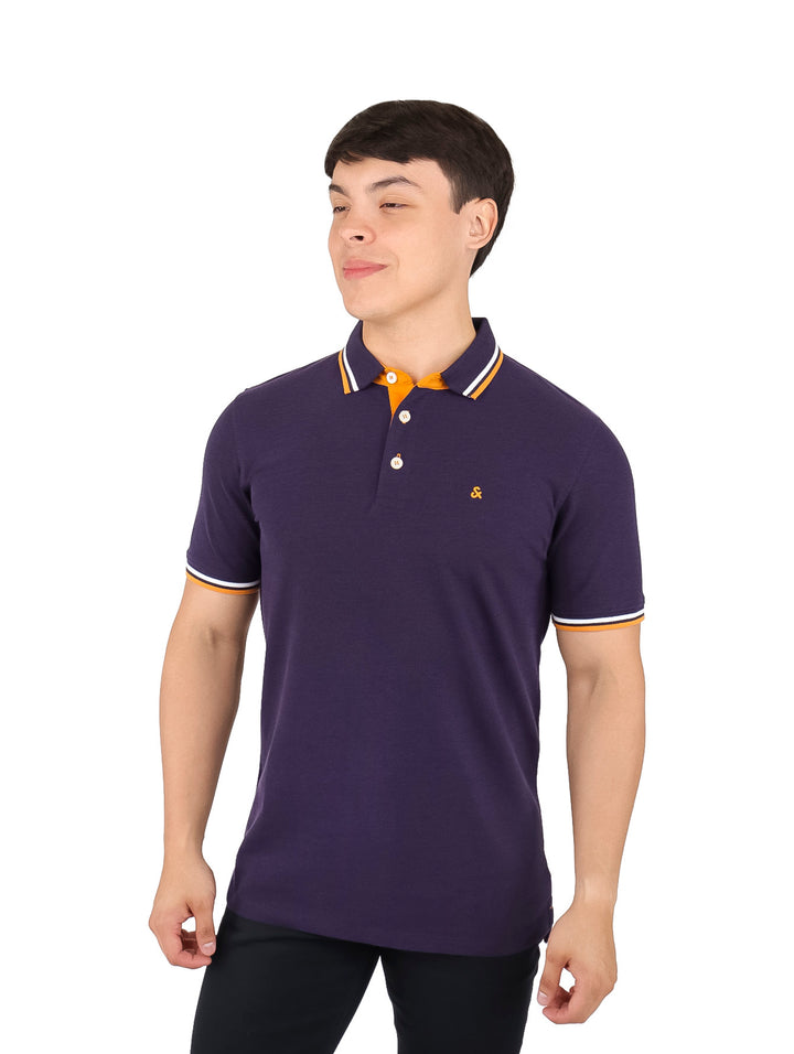 Hombre vistiendo una camiseta polo color morado con detalles naranjas y blancos en el cuello y mangas.