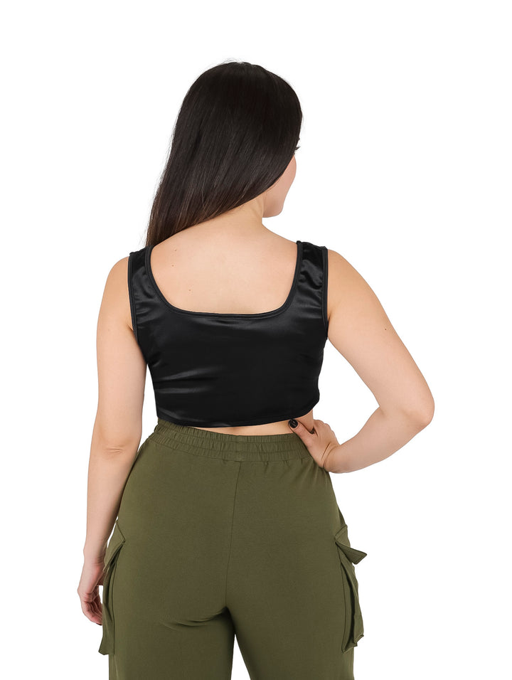 Mujer vistiendo un croptop negro brillante sin mangas con cuello cuadrado y pantalones cargo verde oliva.