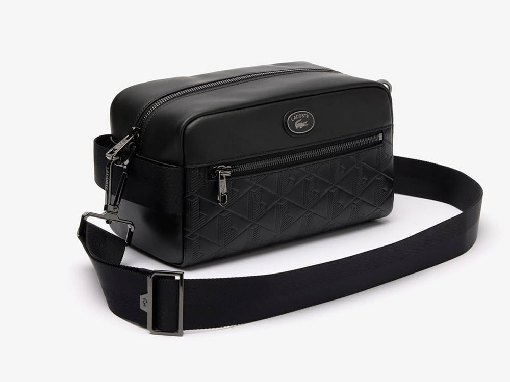 Bolso bandolera Lacoste color negro con textura grabada, correa ajustable y cierre frontal.