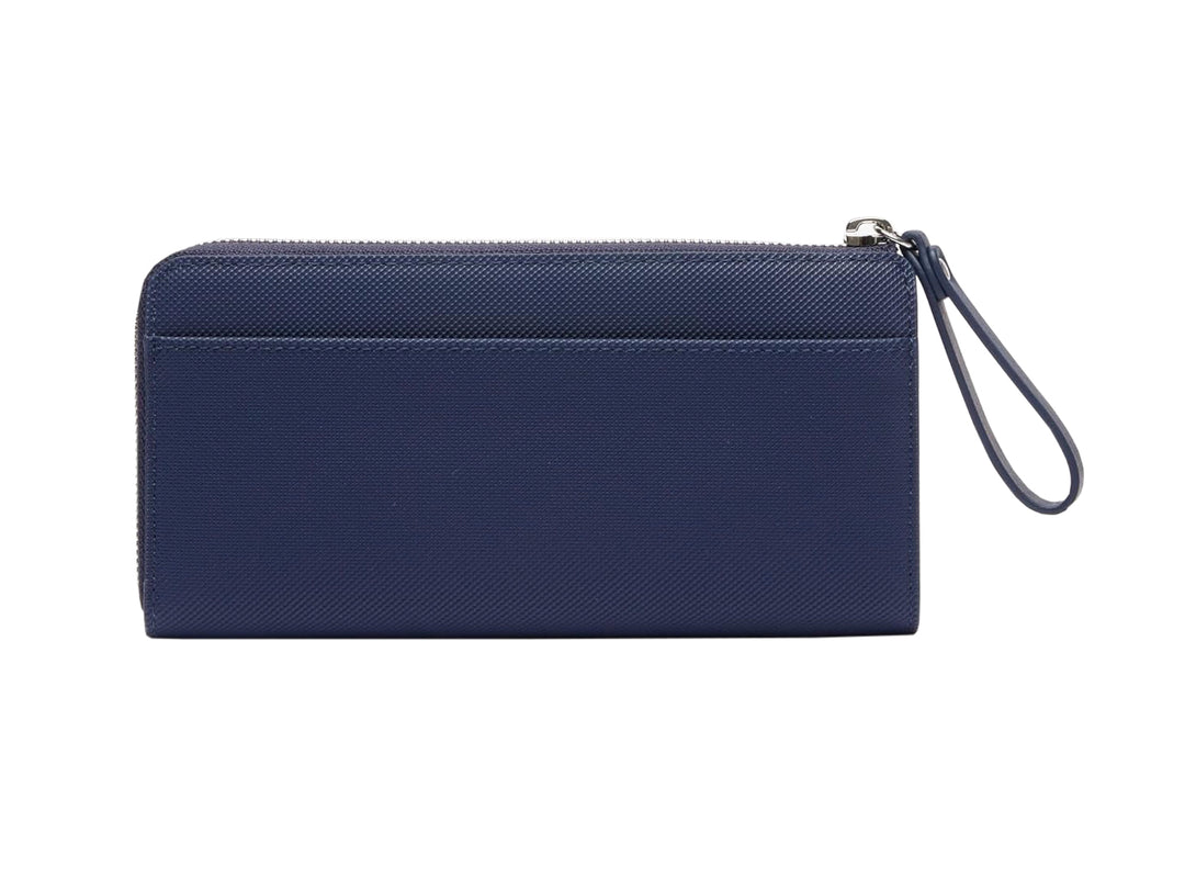 Bolso estilo cartera Lacoste en color azul marino con cierre y logotipo metálico frontal.