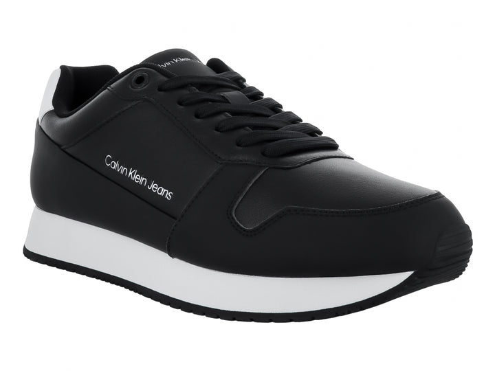 Tenis Calvin Klein color negro con suela blanca y detalles en el talón, estilo retro runner.