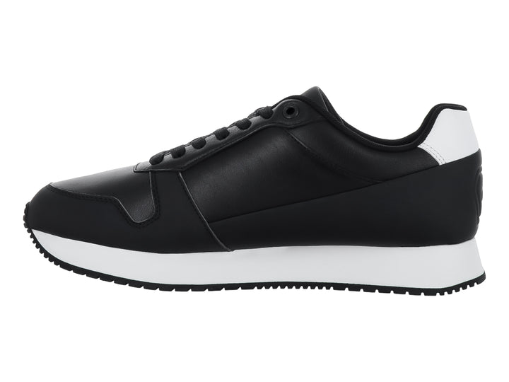 Tenis Calvin Klein color negro con suela blanca y detalles en el talón, estilo retro runner.