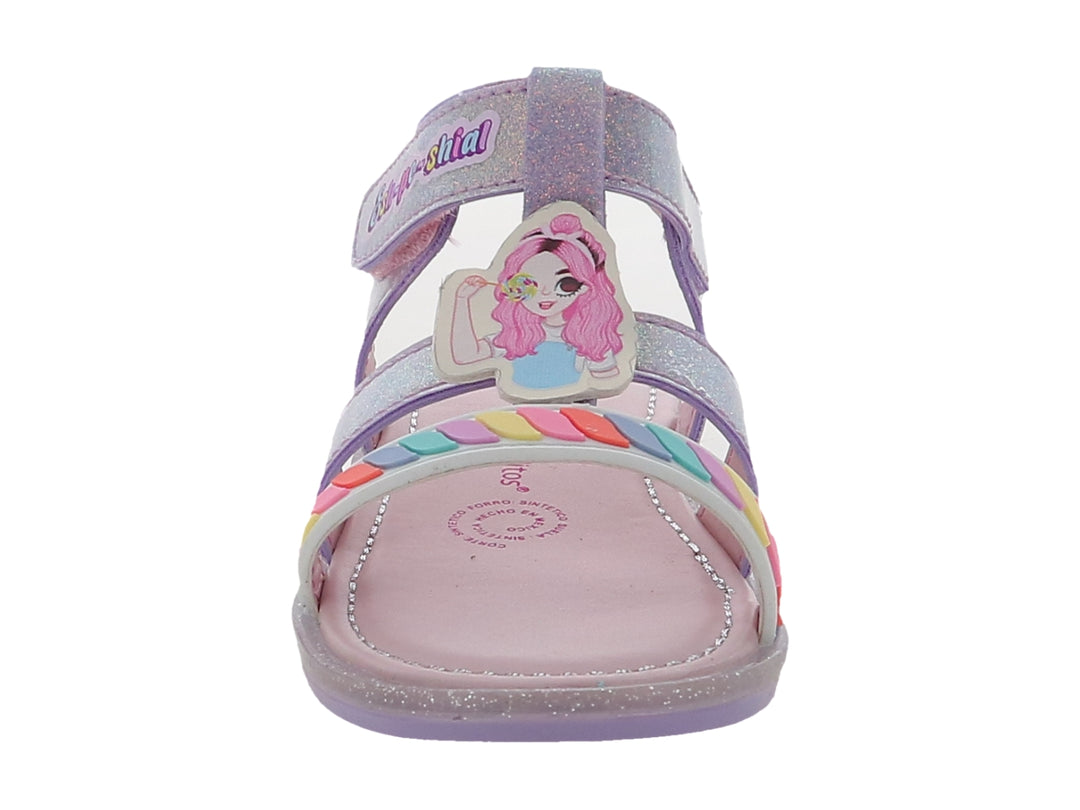Sandalia infantil color lila con acabado brillante, detalles de arcoíris y correa con texto decorativo.