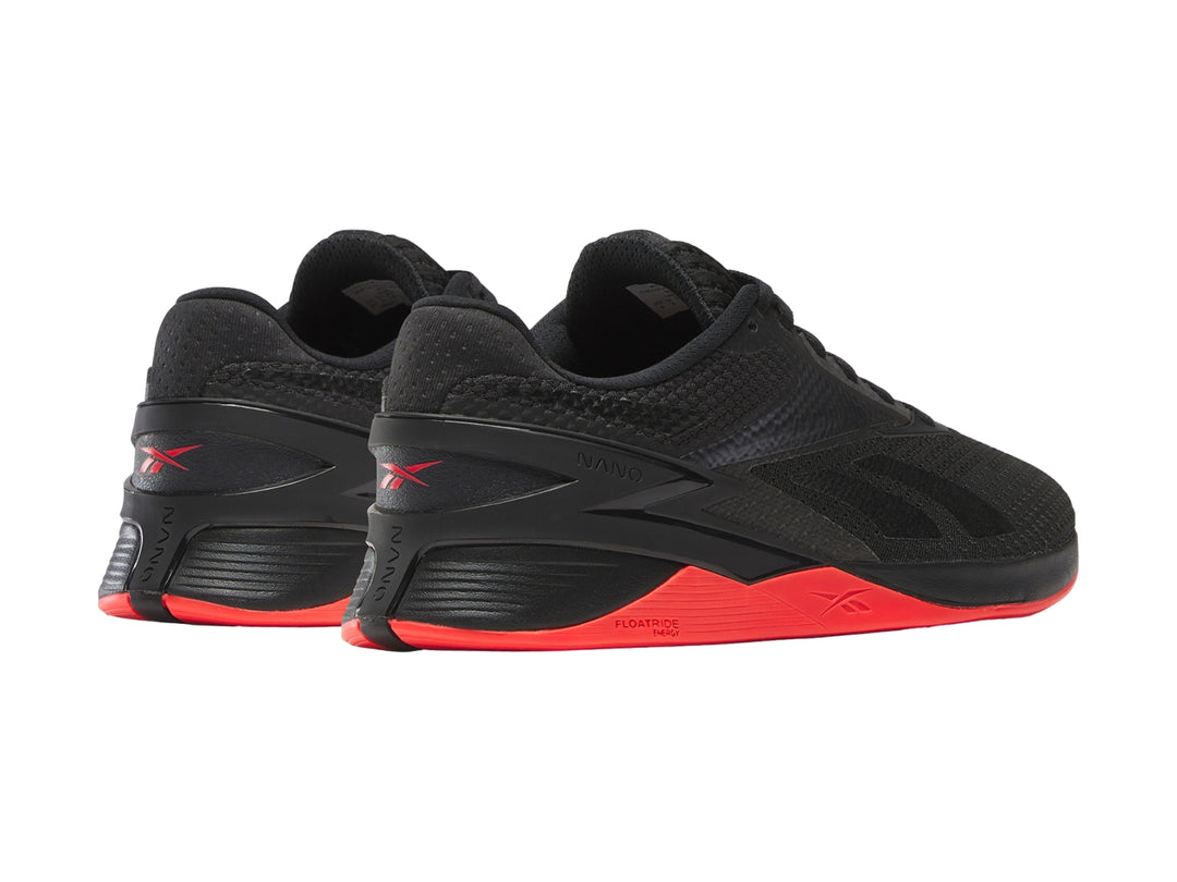 Tenis deportivos Reebok Nano X3 color negro con suela en tono rojo neón.