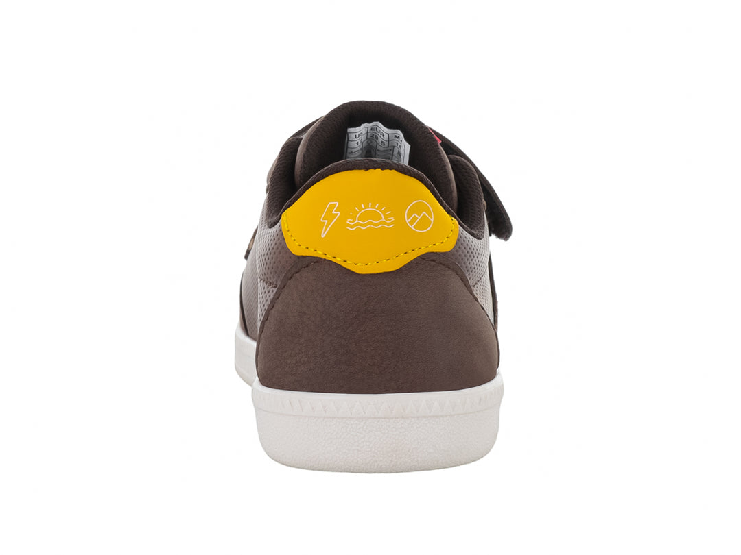 Zapato casual para niño color café con cierre de velcro, suela blanca y detalles en amarillo y rojo.