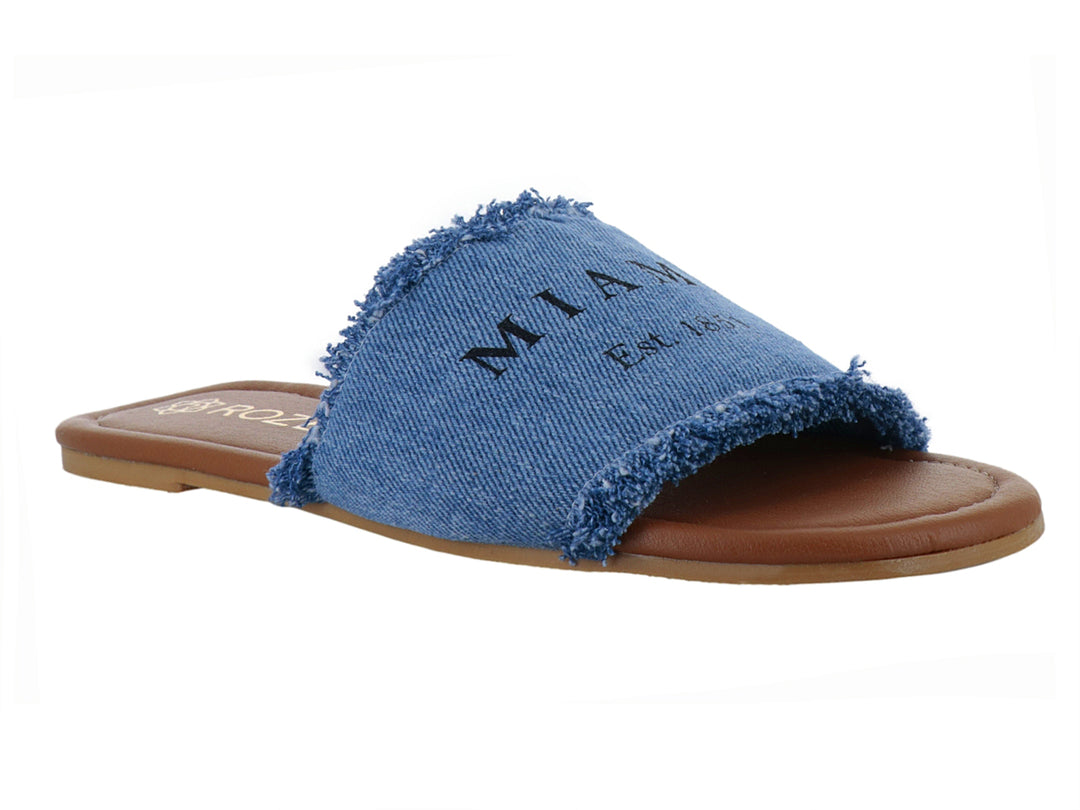 Sandalia plana de marca ROZE con banda superior de tela tipo mezclilla azul con bordes deshilachados y suela café.