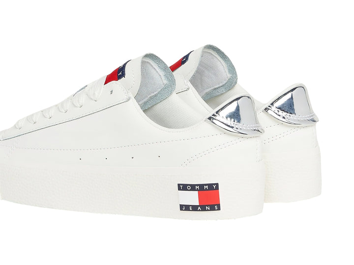 Tenis Tommy Hilfiger color ecru con suela de plataforma blanca y detalle plateado en el talón.