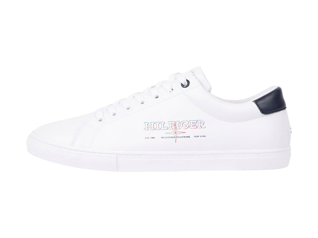 Tenis blancos de Tommy Hilfiger con detalle en azul marino en el talón y suela blanca.