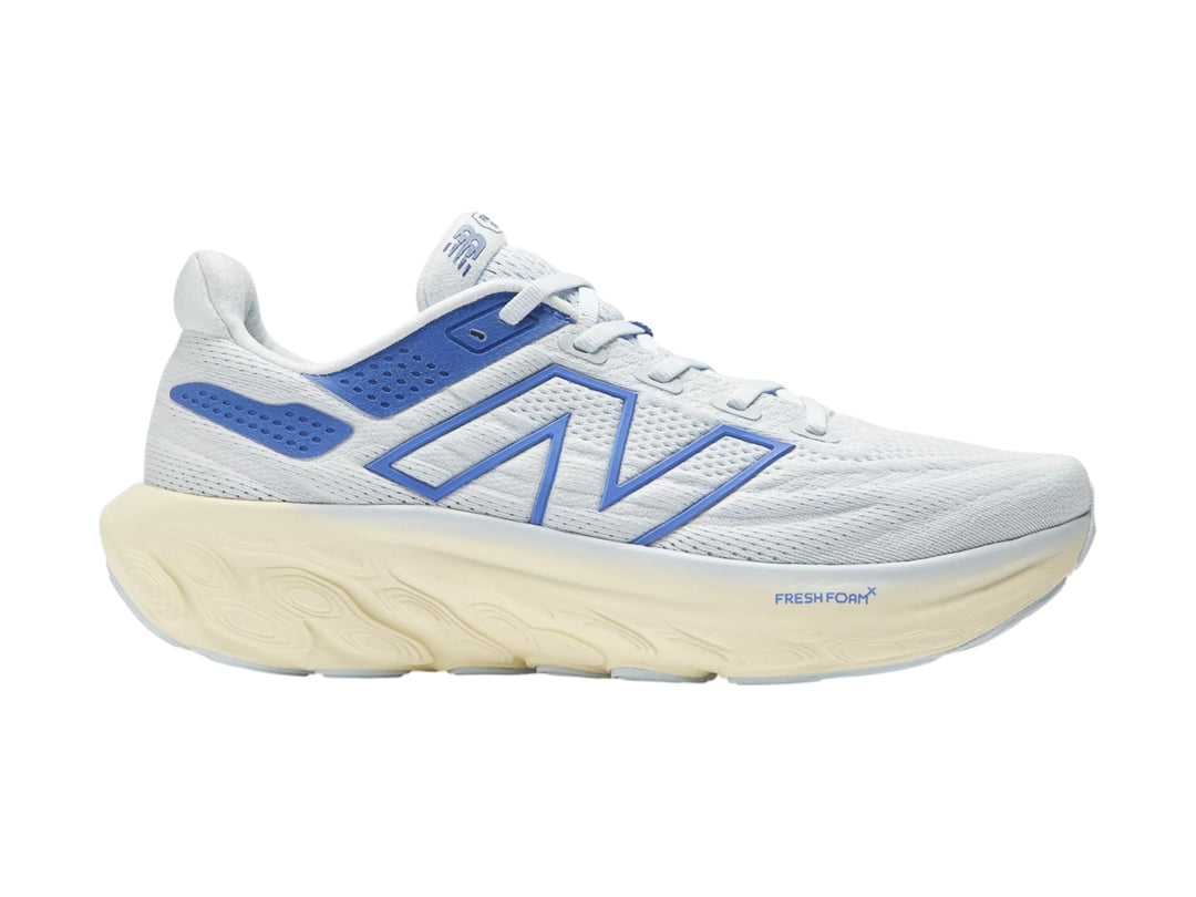 Tenis deportivos New Balance color blanco con detalles en azul y suela gruesa color crema.