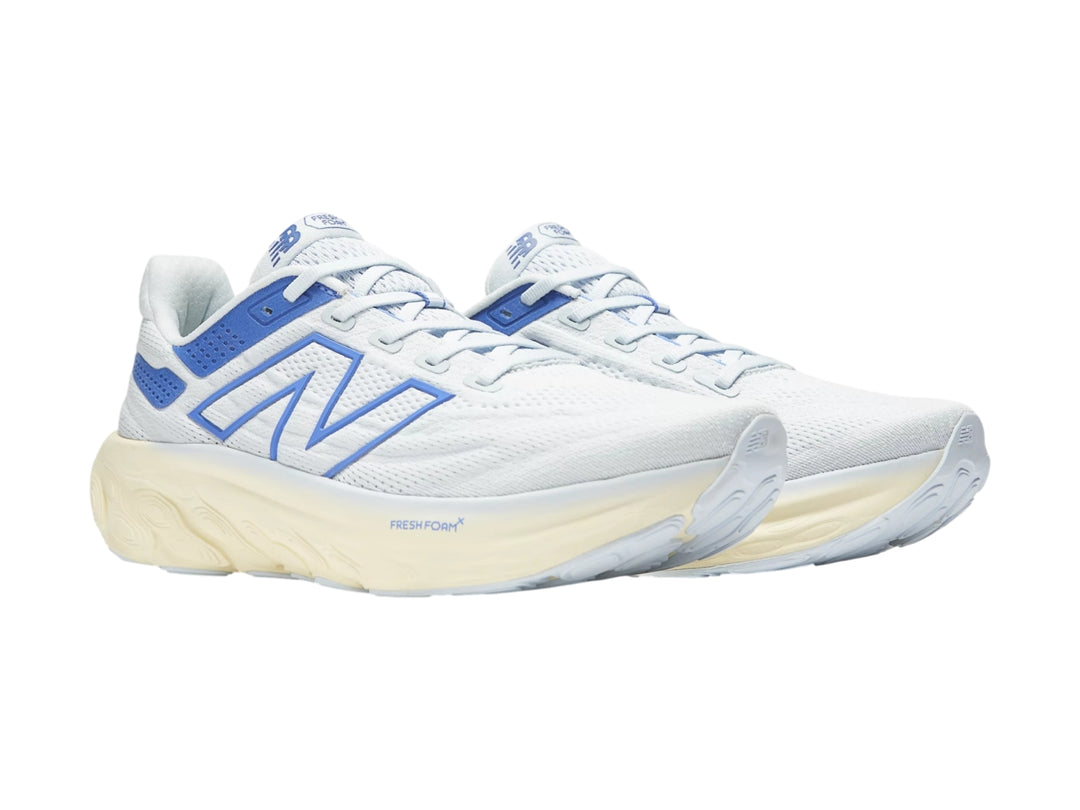 Tenis deportivos New Balance color blanco con detalles en azul y suela gruesa color crema.