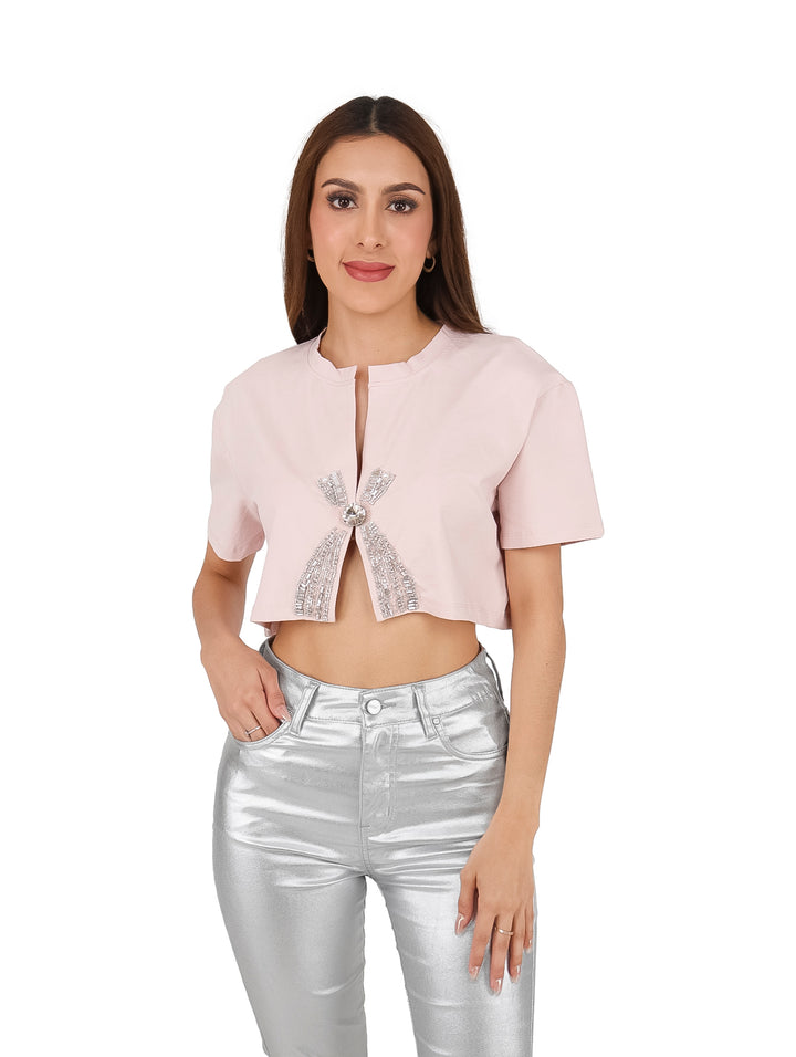 Blusa corta color rosa con detalles de piedras brillantes en el centro.