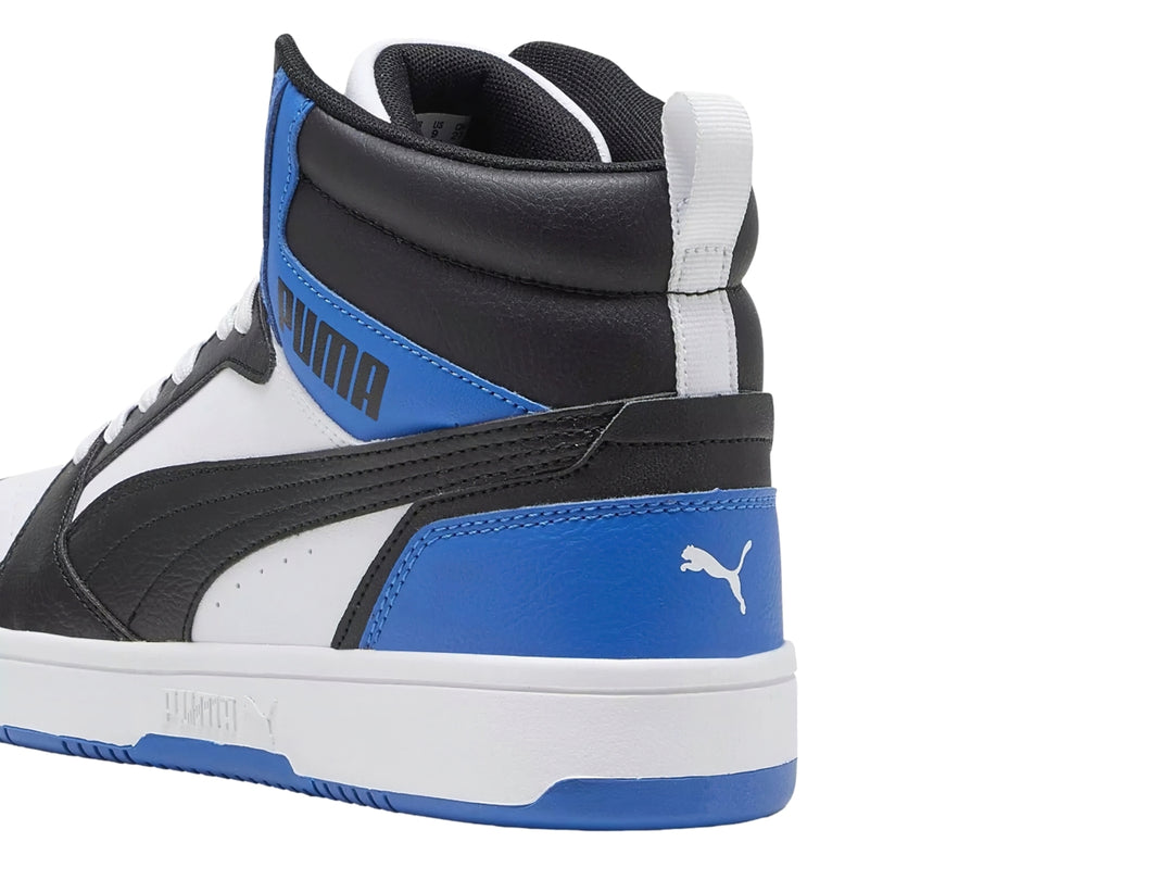 Tenis PUMA Rebound V6 de corte alto en colores blanco, negro y azul royal con suela blanca.