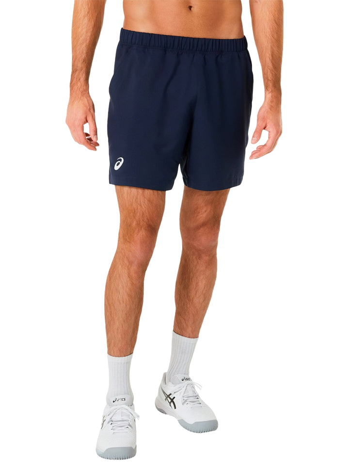 Hombre usando shorts deportivos ASICS color azul midnight con tenis blancos.