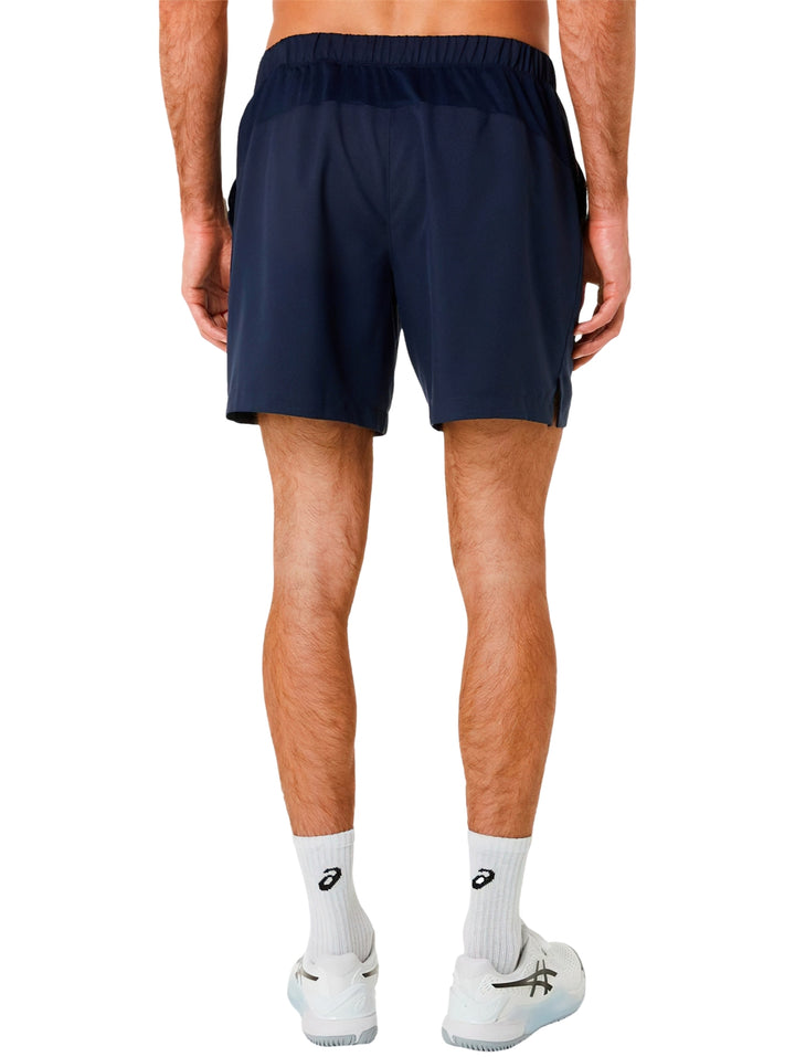 Hombre usando shorts deportivos ASICS color azul midnight con tenis blancos.