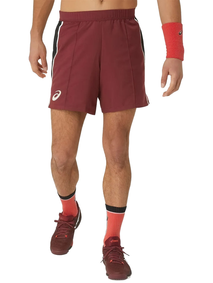 Hombre vistiendo shorts deportivos ASICS color rojo antique red con franjas laterales negras.