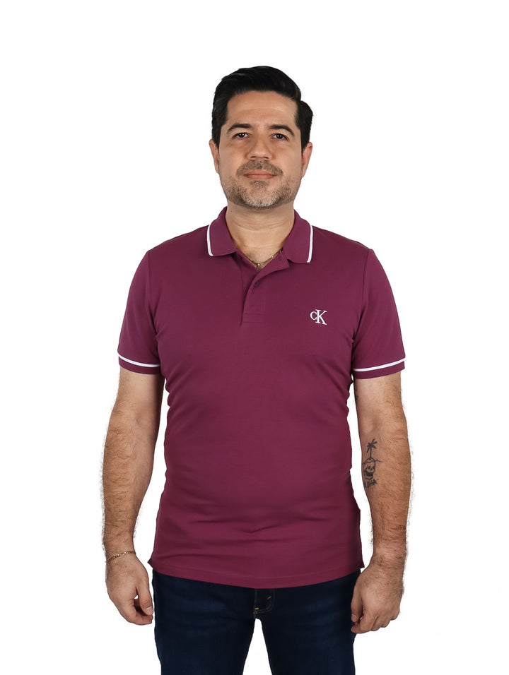 Hombre vistiendo una playera polo color morado de Calvin Klein con detalles blancos en cuello y mangas.