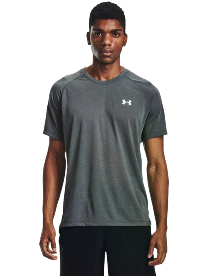 Hombre vistiendo una camiseta deportiva de manga corta color gris oscuro con logotipo blanco de Under Armour.