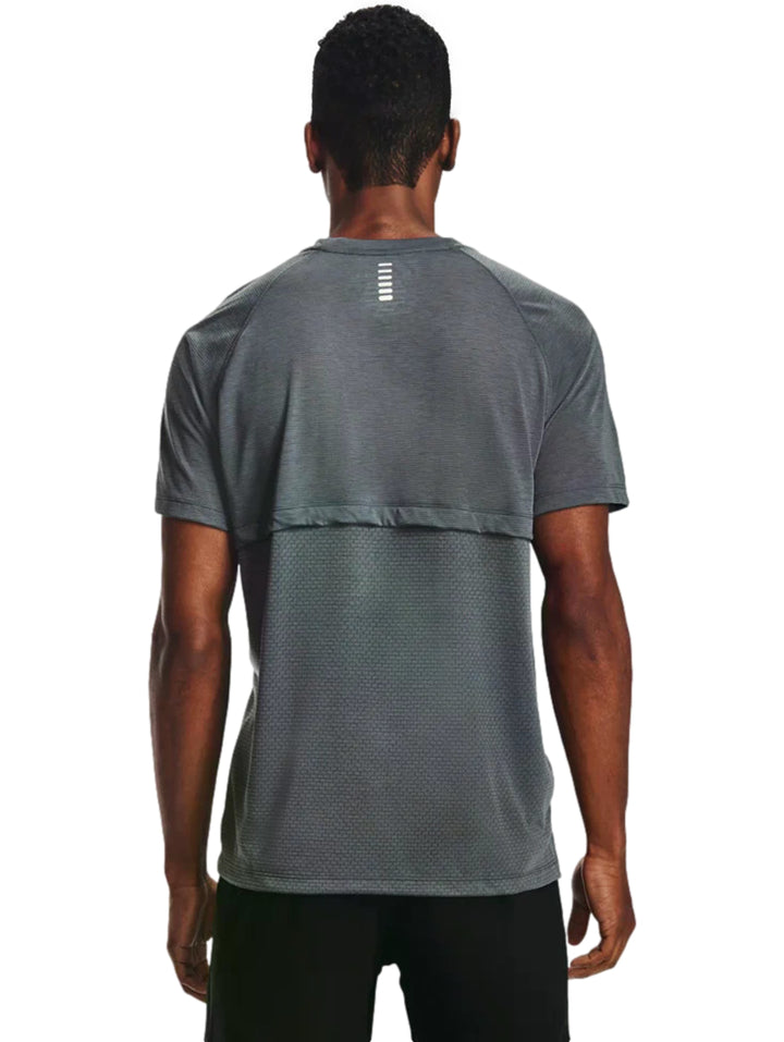 Hombre vistiendo una camiseta deportiva de manga corta color gris oscuro con logotipo blanco de Under Armour.
