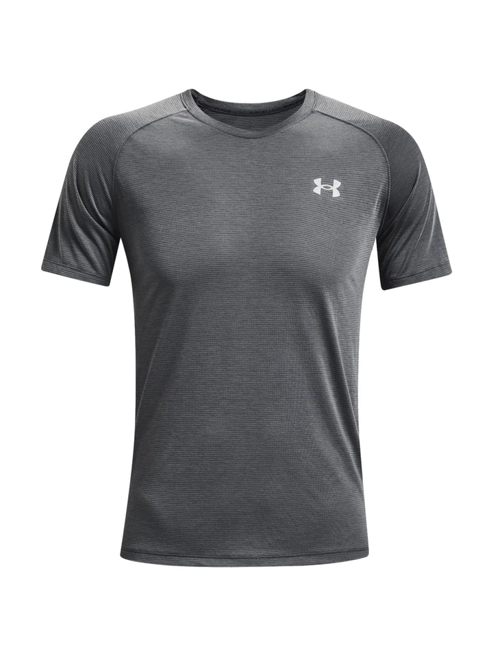 Hombre vistiendo una camiseta deportiva de manga corta color gris oscuro con logotipo blanco de Under Armour.