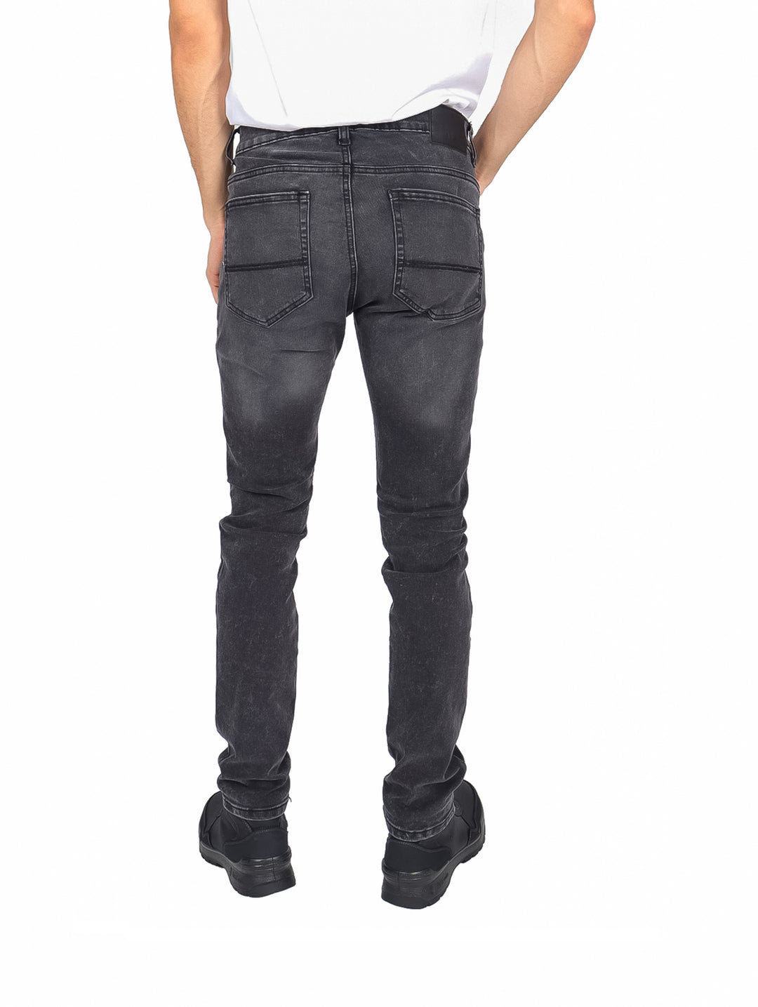 Hombre usando pantalón negro de mezclilla con roturas en las rodillas.