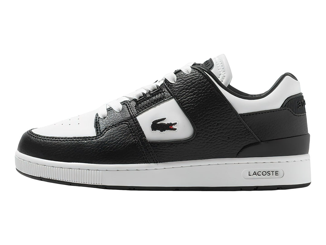 Tenis deportivos Lacoste de cuero en colores blanco y negro con suela blanca y logo del cocodrilo.