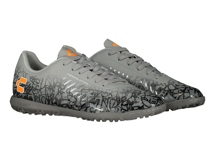 Zapato de fútbol Charly color gris con patrones negros y detalles en naranja, suela para turf.