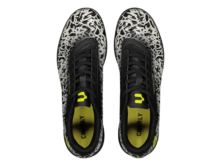 Tenis de fútbol Charly en color negro y blanco con diseño de graffiti y detalles amarillos.