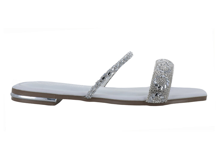 Sandalia plana blanca para niña con tiras decoradas con pedrería brillante plateada.