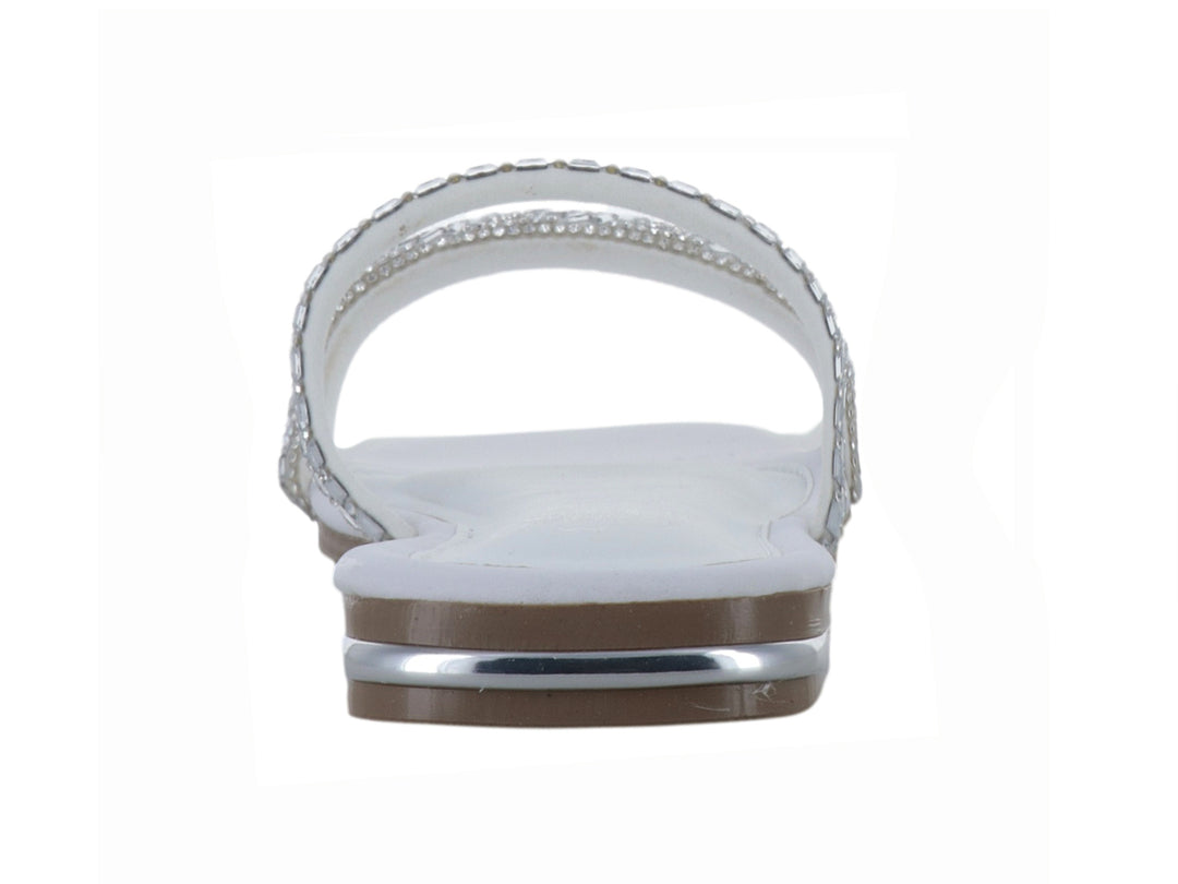 Sandalia plana blanca para niña con tiras decoradas con pedrería brillante plateada.