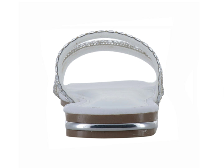 Sandalia plana blanca para niña con tiras decoradas con pedrería brillante plateada.