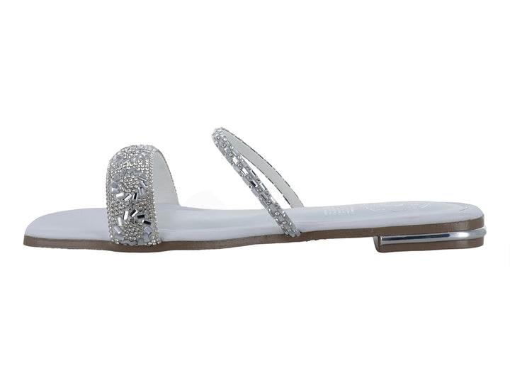 Sandalia plana blanca para niña con tiras decoradas con pedrería brillante plateada.