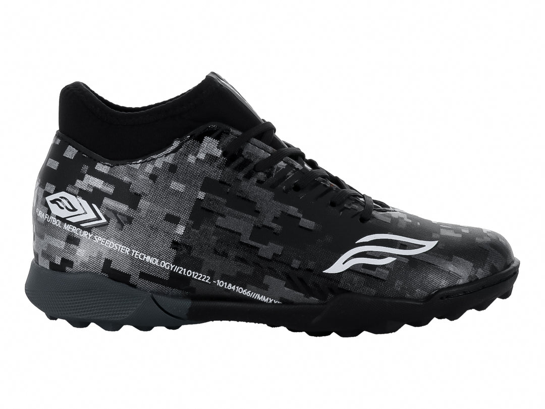 Calzado de fútbol Furia para niños en color negro y plata con patrón pixelado y suela para césped sintético.