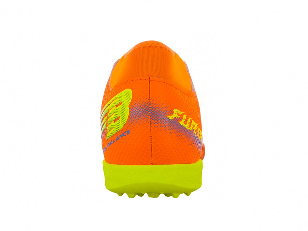 Zapato de fútbol Furia color naranja con suela verde lima y detalles decorativos laterales.