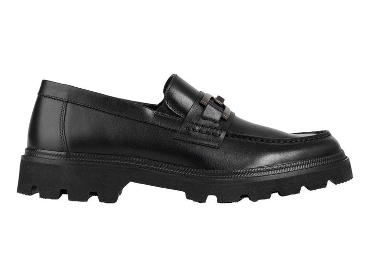 Zapato mocasín negro con suela track gruesa y detalle metálico en la parte superior.