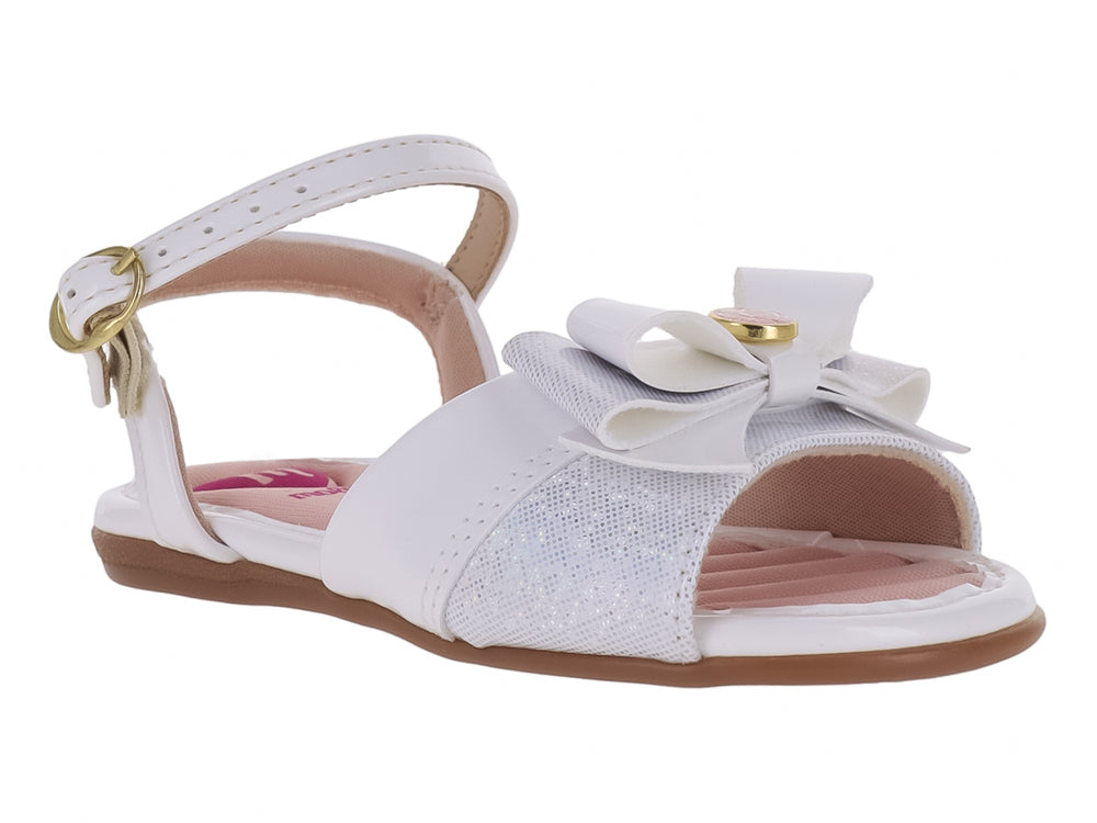 Sandalia blanca para niña con acabado brillante, detalle de moño frontal y correa con hebilla dorada.