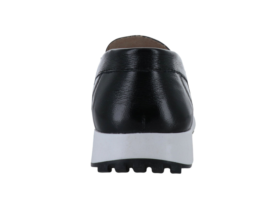 Zapato mocasín negro con suela blanca gruesa y detalle metálico superior.
