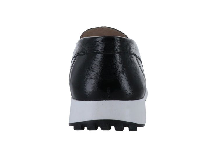 Zapato mocasín negro con suela blanca gruesa y detalle metálico superior.