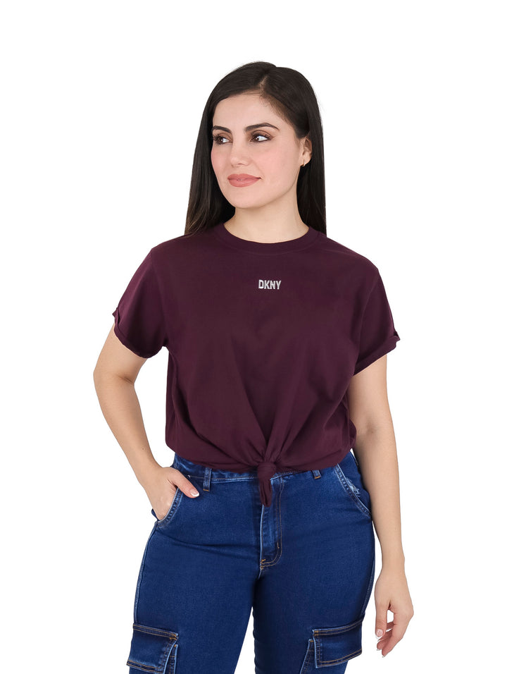 Mujer vistiendo camiseta color borgoña DKNY de corte boxy con nudo en la cintura.